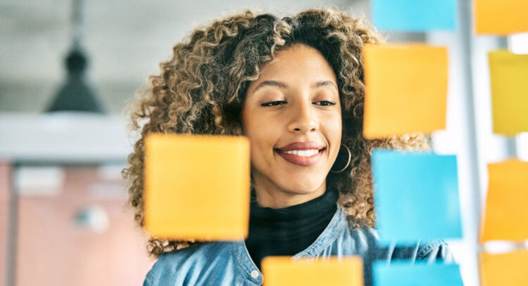 woman looking at post its ona glass board
