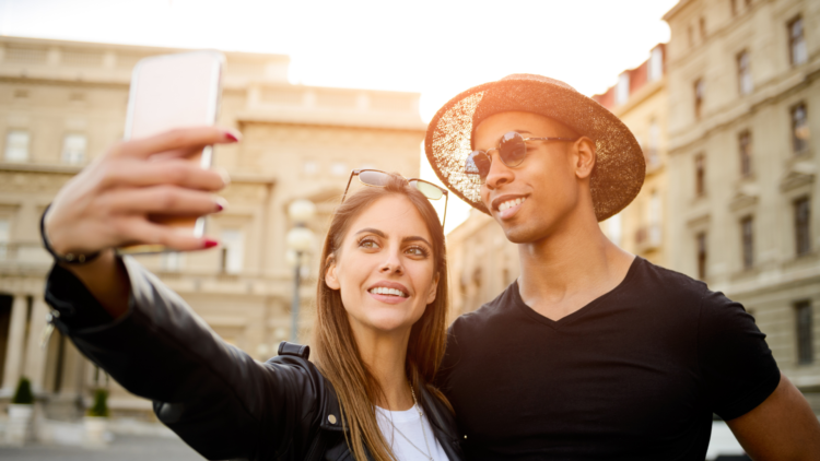 A smiling couple taking a selfie together outside