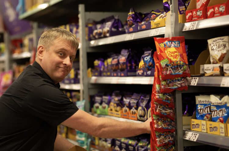 asda worker stacking shelves with sweets