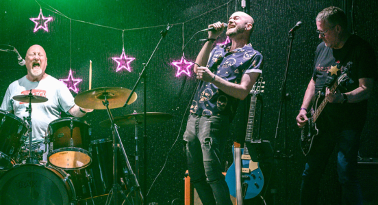 band singing with purple star lights in the background and drummer