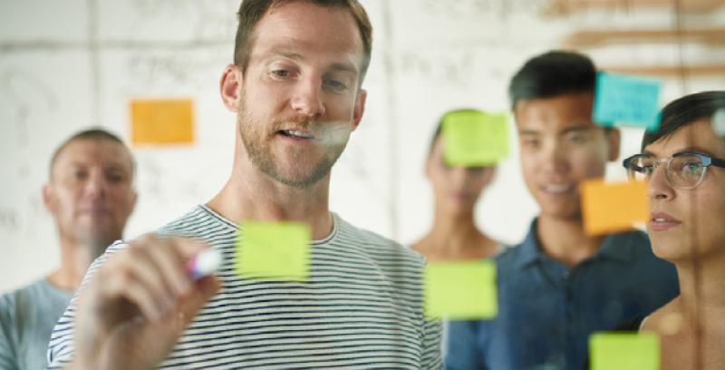 team members putting post-it notes on an interactive board