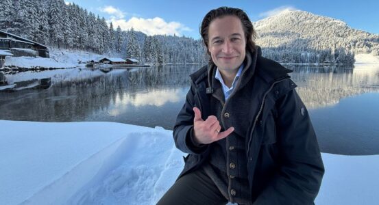 Flo in sat in front of a snow-laden lakeside landscape in Spritzingsee, Bavaria